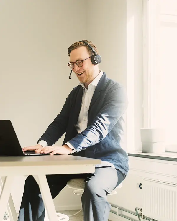 En man vid ett skrivbord ler emot kameran