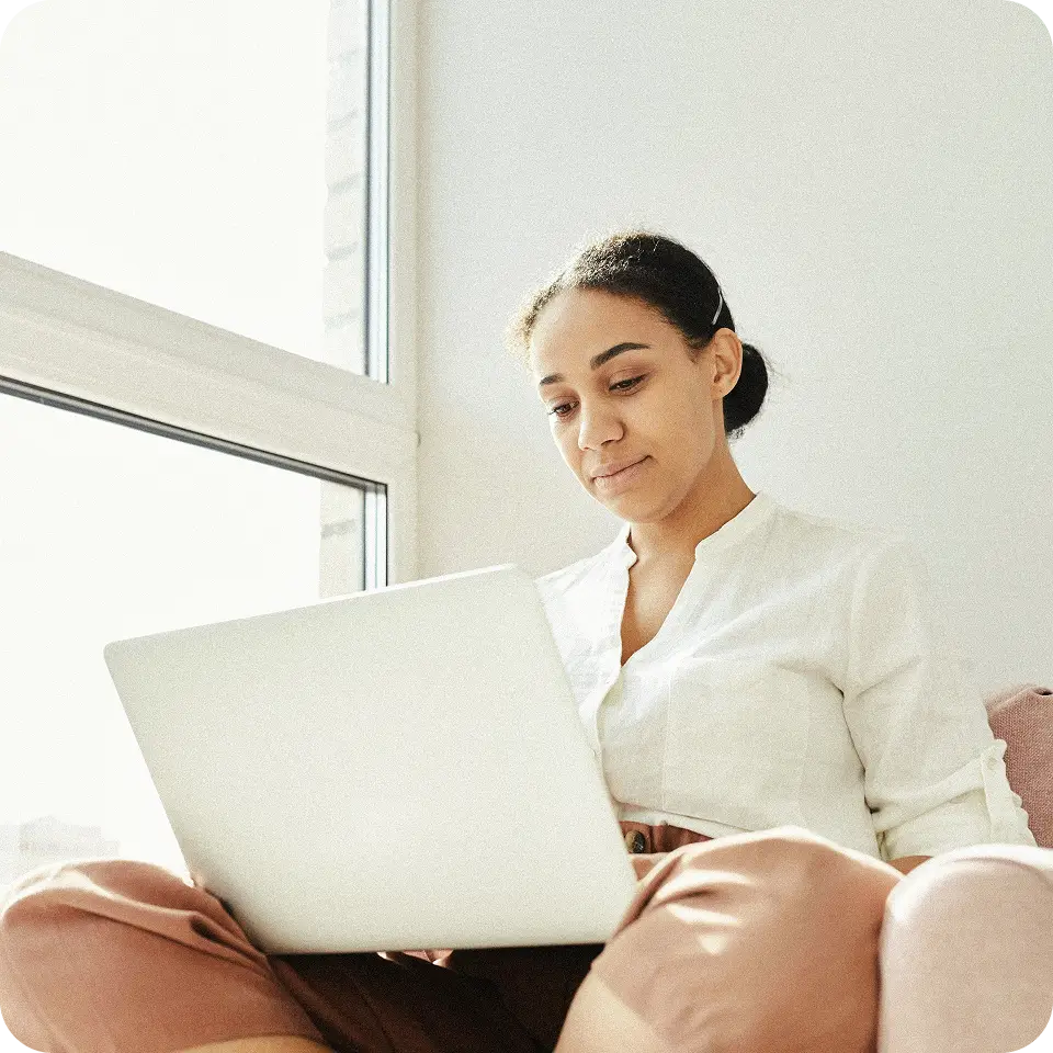 En kvinna som jobbar framför en laptop.